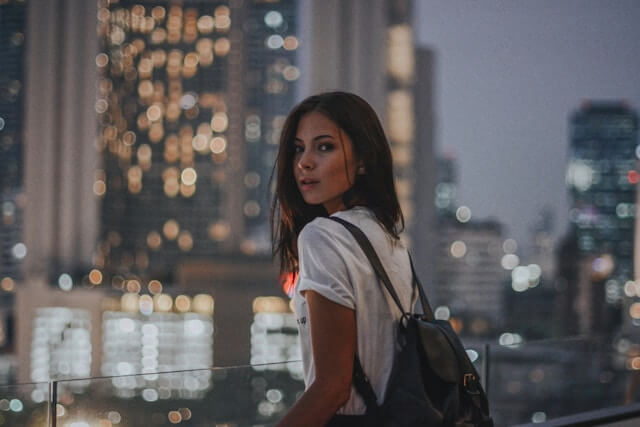 woman with backpack gazing at the city skyline at night