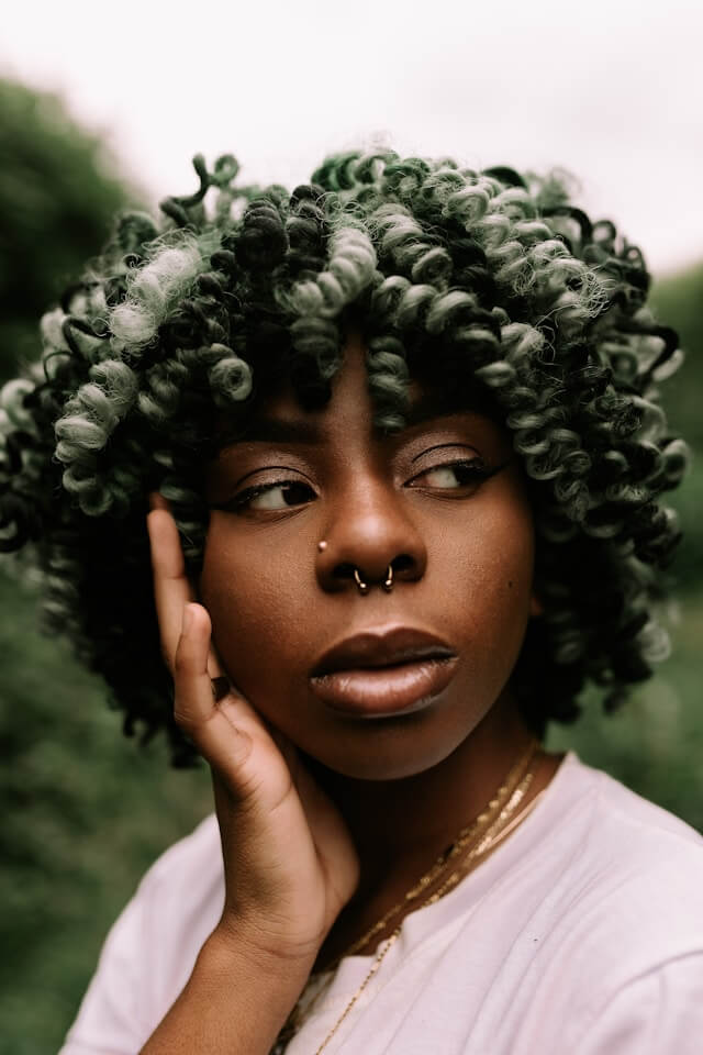 woman with a nose piercing and green afro, portrait style