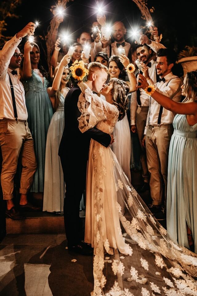 bride and groom kissing in front of a crowd holding sparklers